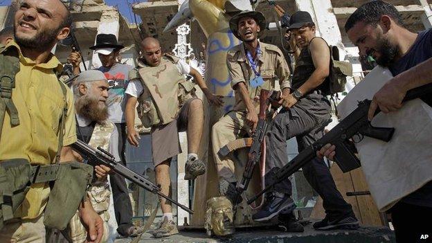 Rebel fighters celebrate as they pose with the toppled head of a Gaddafi statue in Gaddafi 's compound in Bab Al-Aziziya in Tripoli, Libya, Wednesday, 24 August, 2011.