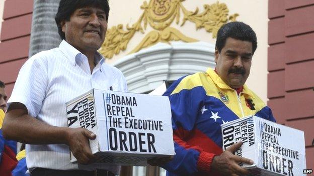 Venezuelan President Nicolas Maduro (R) and Bolivian President Evo Morales hold boxes containing the signatures demanding the repeal of the decree imposed by the United States government during a rally at the Miraflores presidential palace in Caracas on 9 April 2015