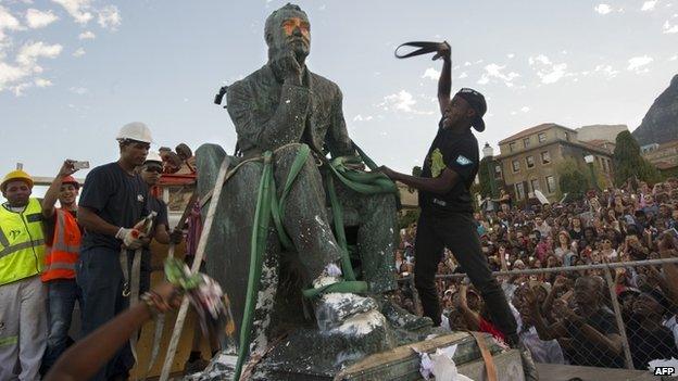 Students attack the defaced statue of British mining magnate and politician, Cecil John Rhodes, as it is removed by a crane from its position at the University of Cape Town on April 9, 2015, in Cape Town