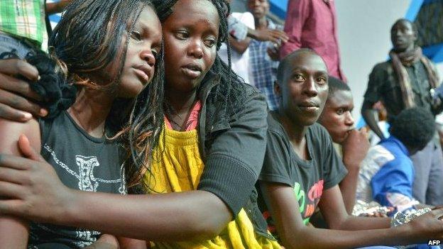 A survivor of an attack by Islamist gunmen on a university campus in Garissa, northern Kenya, is comforted by a colleague after arriving in Nairobi on 4 April 2015