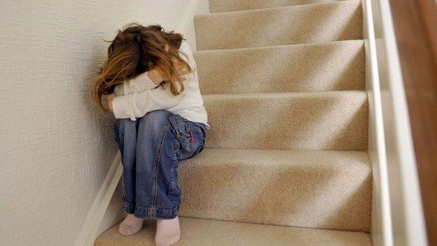 Library image of young girl sitting on a staircase, covering her face