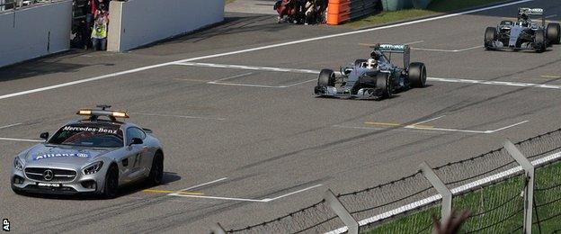 Lewis Hamilton crosses the line behind the safety car to win the Chinese Grand Prix