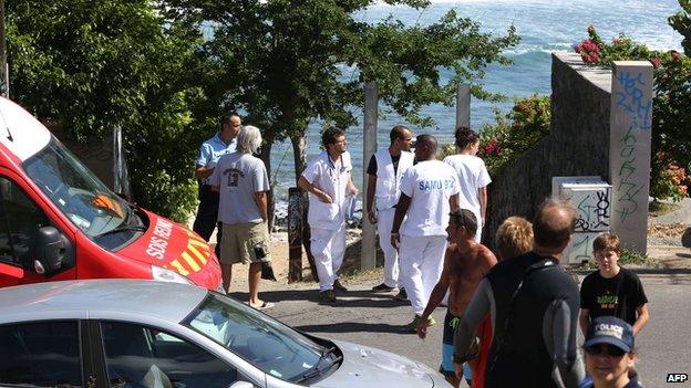 Rescuers and onlookers stand near the beach in Les Aigrettes where the boy was killed on 12 April 2015