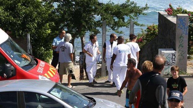 Rescuers and onlookers stand near the beach in Les Aigrettes where the boy was killed on 12 April 2015