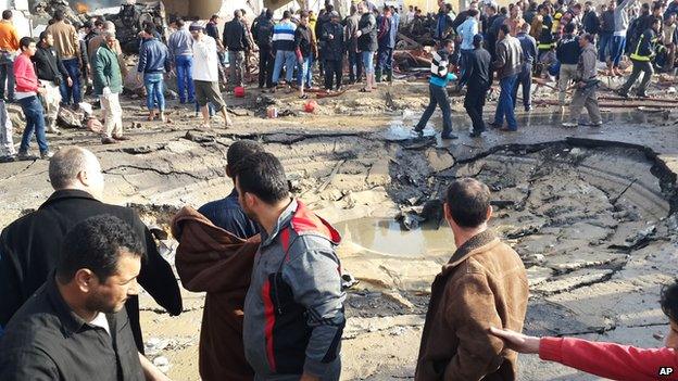 Egyptians gather around a crater left after a bombing in El-Arish on 11 April, 2015