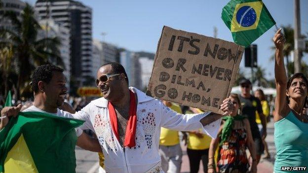 A man disguised as US singer Elvis Presley holds a placard during a protest against the government of Brazilian President Dilma Rousseff at Copacabana beach in Rio de Janeiro, Brazil on 12 April 2015