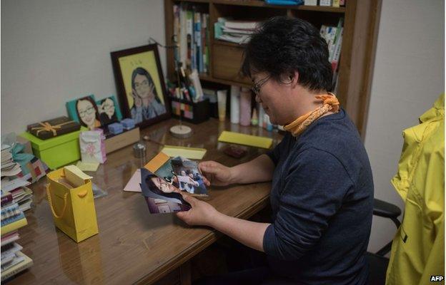 In a photo taken on 11 April 2015 Lee Keum-Hui looks at photos in the bedroom of her daughter Cho Eun-Hwa, a victim of the Sewol ferry disaster who remains unaccounted for, in Ansan