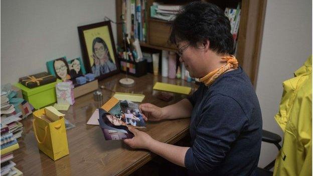 In a photo taken on 11 April 2015 Lee Keum-Hui looks at photos in the bedroom of her daughter Cho Eun-Hwa, a victim of the Sewol ferry disaster who remains unaccounted for, in Ansan