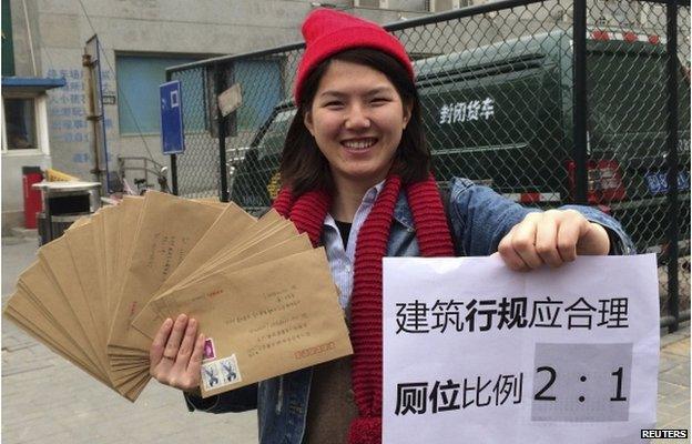 Women activist Li Tingting, 25, poses with letters and a paper which read "Construction regulations should be reasonable, bathroom proportion 2:1 (women/men)" in this undated file handout picture taken in an unknown location in China, provided by a women"s rights group on 8 April 2015