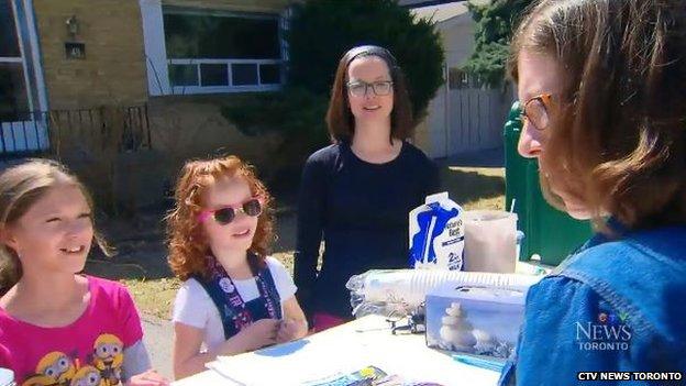 Na'ama Uzan, her mother and a friend serve a customer at the lemonade stand