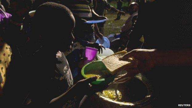 Foreigners queue for food provided by local community members at the sports field in Isipingo, south of Durban