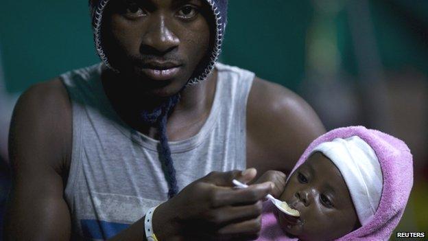 A foreign man feeds his young child in Isipingo, south of Durban