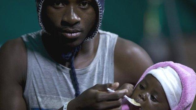 A foreign man feeds his young child in Isipingo, south of Durban