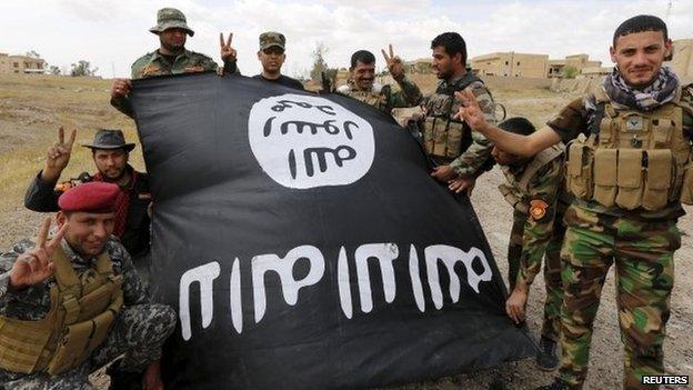 Iraqi government forces, holding an upside down Islamic State flag, celebrate the recapture of Tikrit (1 April 2015)