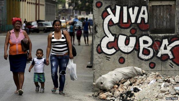 People walk near graffiti that reads "Long live Cuba" in Havana April 11, 2015.