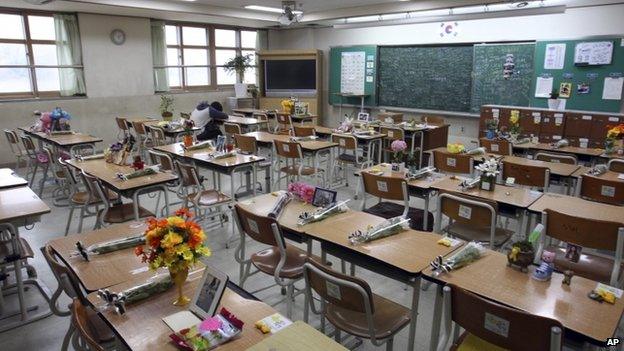 In this 12 April 2015, photo, survivor Yang Jeong-won, a student who was rescued from the sunken Sewol ferry, puts her head on her desk inside a classroom at Danwon High School in Ansan, South Korea, which has become a memorial for her classmates who were killed