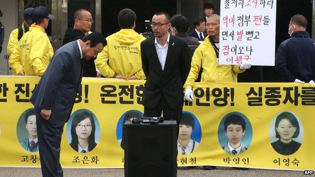 South Korean Prime Minister Lee Wan-Koo (L) bows as he is blocked by family members of the victims of the sunken South Korean ferry Sewol outside a remembrance hall in Ansan on 16 April 2015