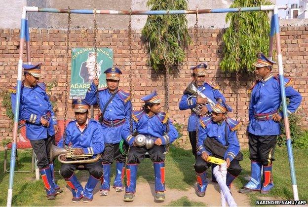 Members of an Indian wedding band gather on swings as they wait for a religious procession at a garden in Amritsar