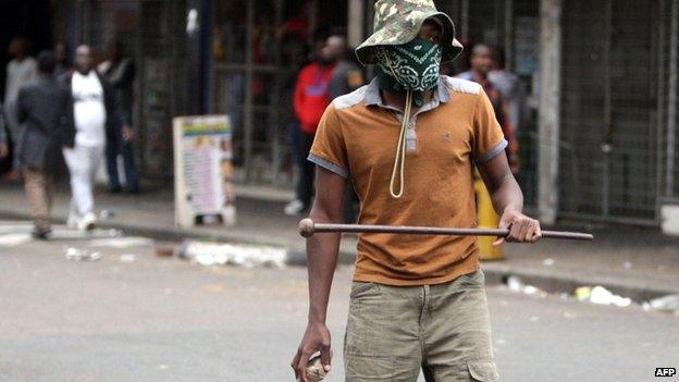 A local resident holds a stone and a traditional Zulu weapon after a skirmish with foreigners as thousands of people take part in the "peace march" against xenophobia in Durban, South Africa, on 16 April 2015