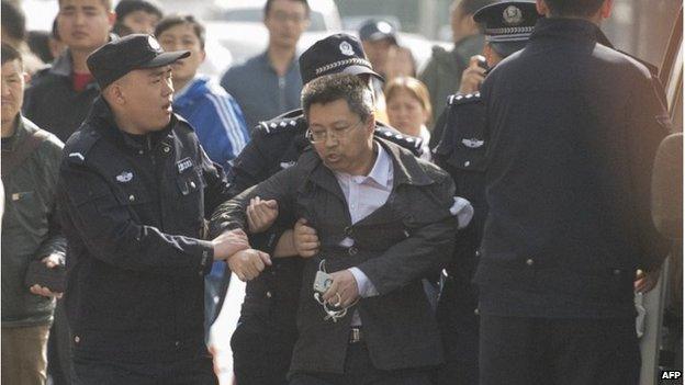 Police remove an unidentified man outside the Beijing court (17 April 2015)