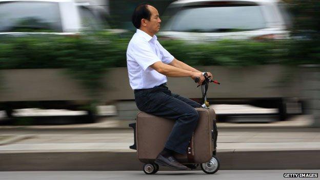 This picture taken on May 28, 2014 shows Chinese farmer He Liangcai riding a motorized scooter suitcase that he has spent the past ten years developing. It can travel up to 12.5mph