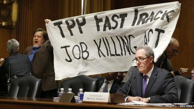 A policewoman removes a man protesting the Trans-Pacific Partnership (TPP) as U.S. Trade Representative Michael Froman (R) testifies before a Senate Finance Committee hearing on "President Obama"s 2015 Trade Policy Agenda" on Capitol Hill in Washington January 27, 2015.