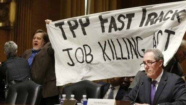 A policewoman removes a man protesting the Trans-Pacific Partnership (TPP) as U.S. Trade Representative Michael Froman (R) testifies before a Senate Finance Committee hearing on "President Obama"s 2015 Trade Policy Agenda" on Capitol Hill in Washington January 27, 2015.