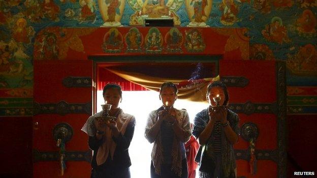 Daughters of Ang Kaji Sherpa, one of the 16 Nepali Sherpa guides who were killed during an avalanche last year, light butter lamps in memory of their father at a monastery in Kathmandu April 18, 2015