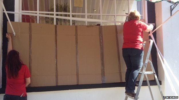 shopkeepers putting cardboard over their shop window