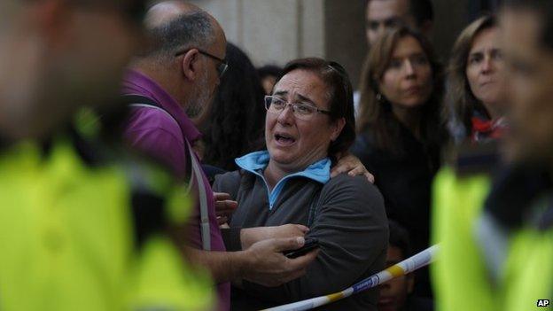 People stand outside a high school in Barcelona, Spain, Monday, April 20, 2015, where a minor has been taken into custody