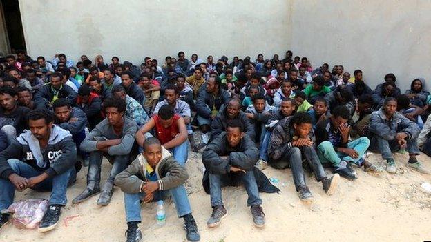 Some of the 340 illegal migrants who were rescued by the Libyan navy off the coast of the western town of Sabratha when their boat began to take on water, sit at a shelter on 12 May 2014