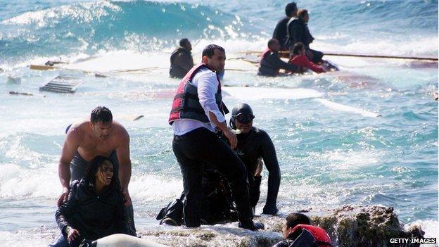 Local residents and rescue workers try to help migrants after their boat sank off the island of Rhodes, Greece