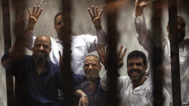 Members of the banned Muslim Brotherhood, Essam al-Erian (C) and Mohamed al-Beltagy (L) along other defendants flash the four-finger sign from behind bars during a trial session, in Cairo, Egypt, 21 April 2015.