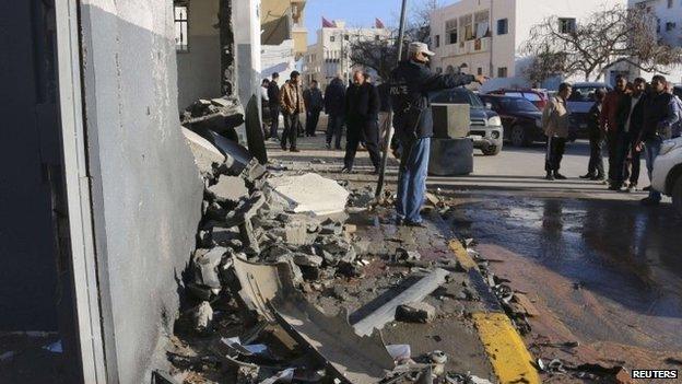 Civilians and security personnel stand at the scene of an explosion - which Islamic State said it carried out - at a police station in Tripoli (12 March 2015)