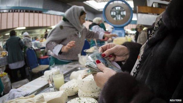 A customer in Almaty's Green Bazaar holds some tenge