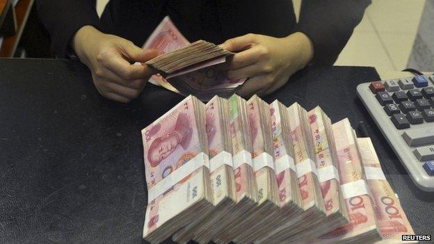 A clerk counts 100 Chinese yuan banknotes