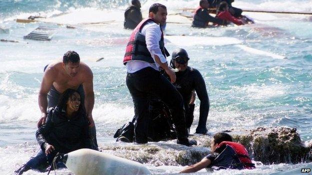 Local residents and rescue workers help a migrant woman after a boat carrying migrants sank off the island of Rhodes, south-eastern Greece