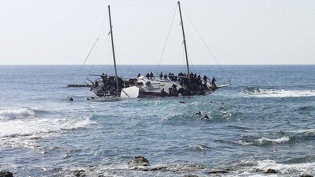 Migrants trying to reach Greece are seen onboard a capsized sailboat