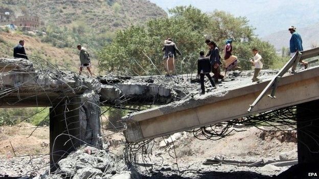 Yemenis walk over a bridge targeted by Saudi-led coalition aircraft in Ibb (21 April 2015)