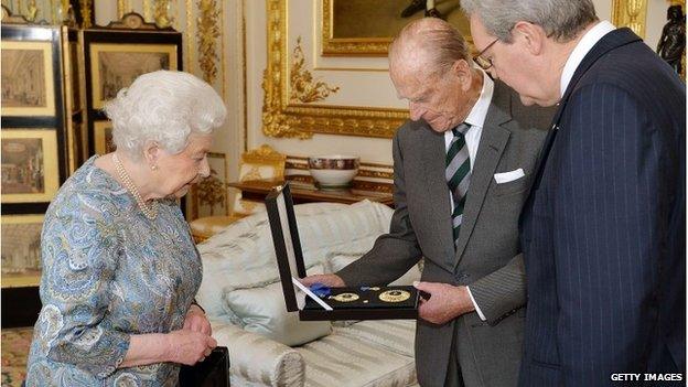 Queen Elizabeth II presents Prince Philip with the Insignia of a Knight of the Order of Australia with Australian High Commissioner Alexander Downer