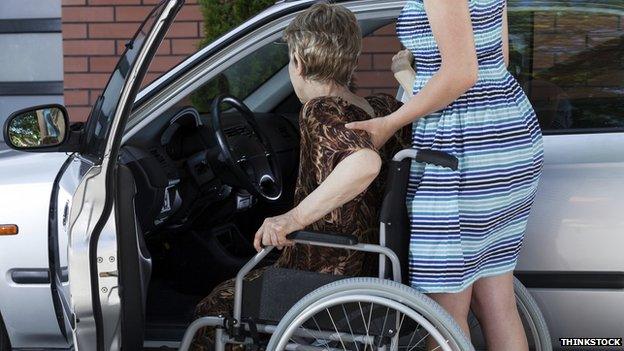 Carer helping woman into car