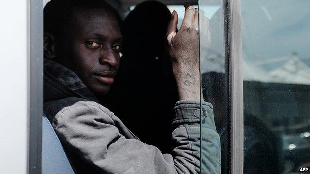 A rescued migrant with a number on his right arm, sits on bus after disembark off the Italian Guardia di Finanza vessel Denaro at the Sicilian harbour of Catania on 23 April 2015