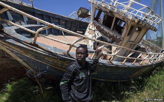 A migrant from Nigeria stands in a "boat graveyard" 22 April 2015 in Lampedusa, Italy.