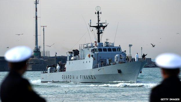 Rescued migrants stand aboard the Italian Guardia di Finanza vessel Denaro upon arrival to the Sicilian harbour of Catania on 23 April 2015.