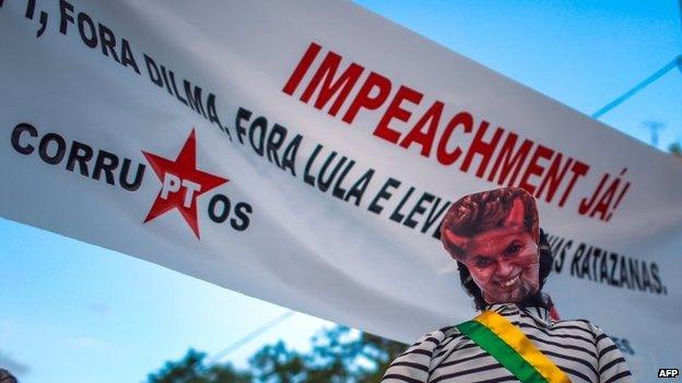 A dummy wearing a mask depicting Brazilian President Dilma Rousseff as a devil is seen with a sign reading "Impeachment now!" during a protest in Porto Alegre on 12 April, 2015