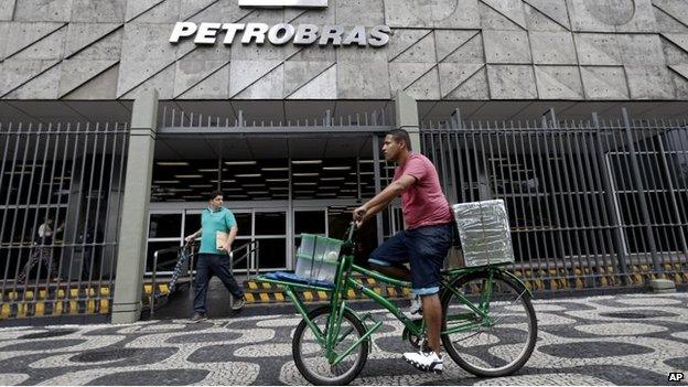 A man rides a bike in front of the Petrobras headquarters in Rio de Janeiro, Brazil, Wednesday, April 22, 2015