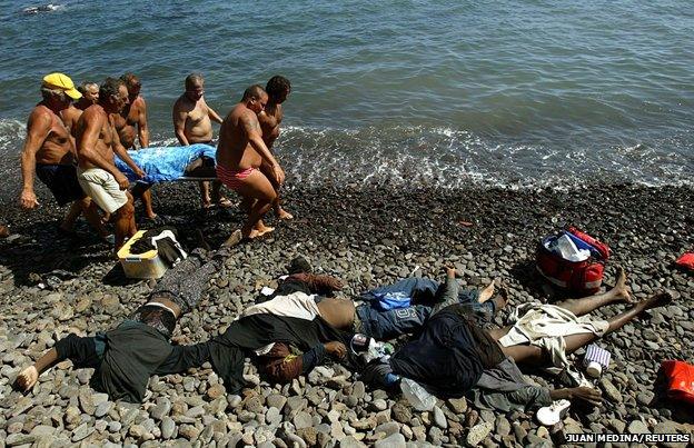 Spain, 2004 - rescuers pull a body out of the sea - several already lie on the beach