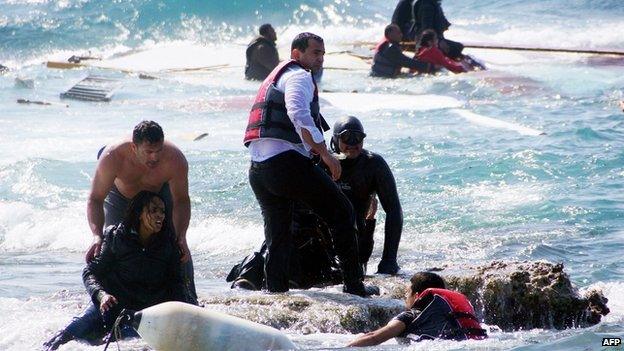 Local residents and rescue workers help a migrant woman after a boat carrying migrants sank off the island of Rhodes, southeastern Greece, 20 April 2015