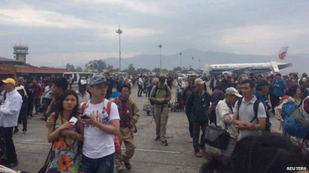 People stand on the runway outside the International Terminal after a earthquake hit, at Tribhuvan International Airport, Kathmandu, Nepal, April 25, 2015,