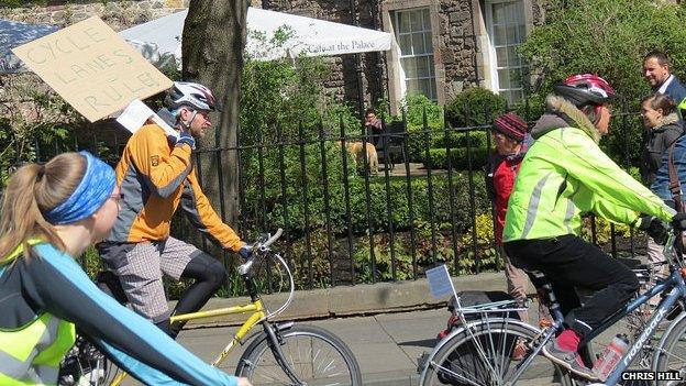 mAN RIDING A BIKE AND CARRYING A PLACARD